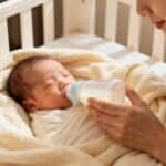 Baby receiving milk bottle from mother in cozy nursery.